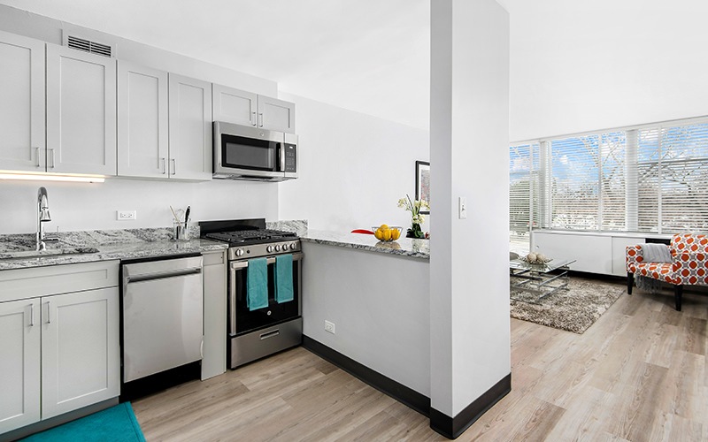 Bright kitchen with stainless steel appliances viewing the living room